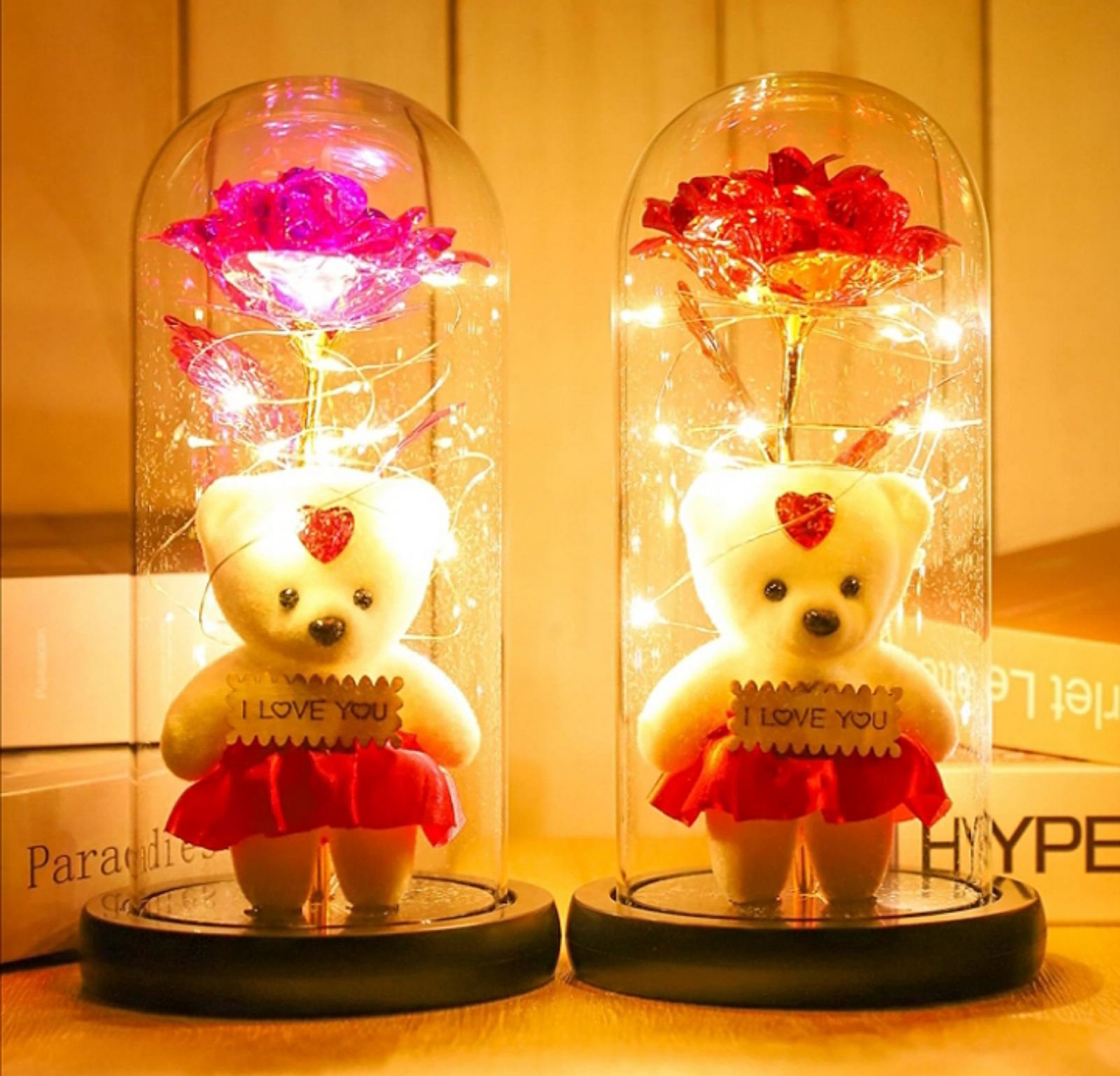 Romantično osvetljena staklena kupola sa LED svetlima oko crvene ruže i medvedića.