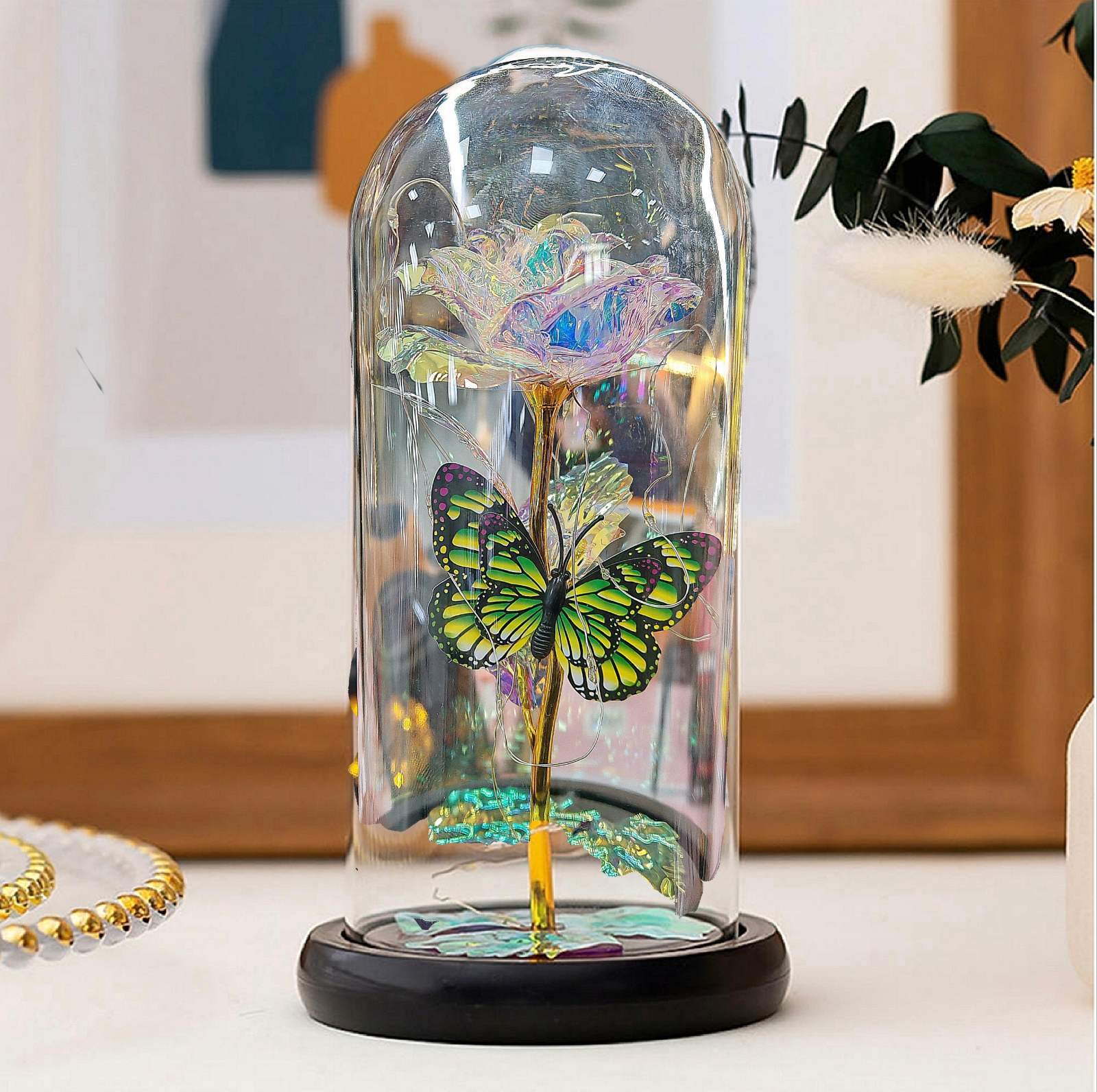 Raznobojna večna ruža u staklenom zvonu sa zelenim leptirom na beloj podlozi