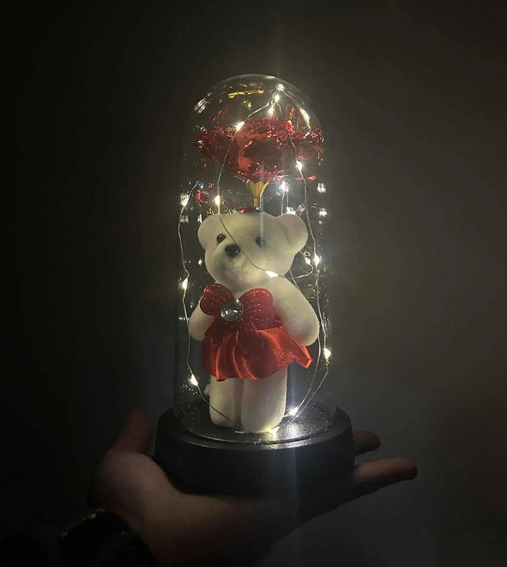 Elegantna crna baza staklene kupole sa osvetljenjem koje ističe crvenu ružu.