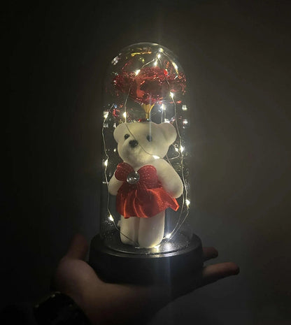 Elegantna crna baza staklene kupole sa osvetljenjem koje ističe crvenu ružu.